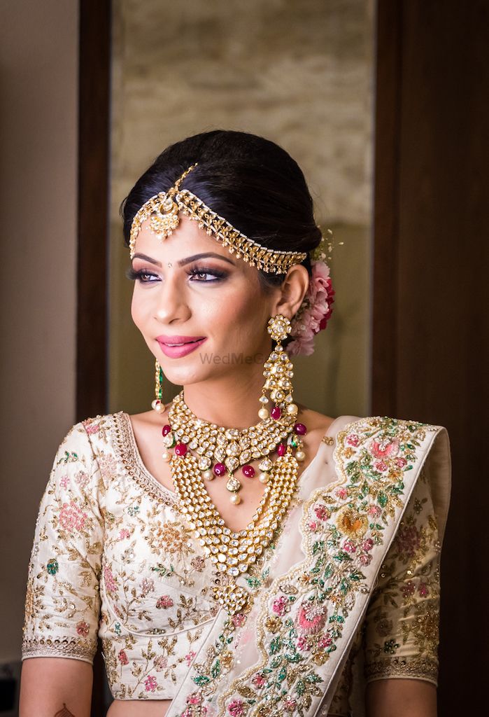Photo of A bride poses in their ivory lehenga and unique jewelry