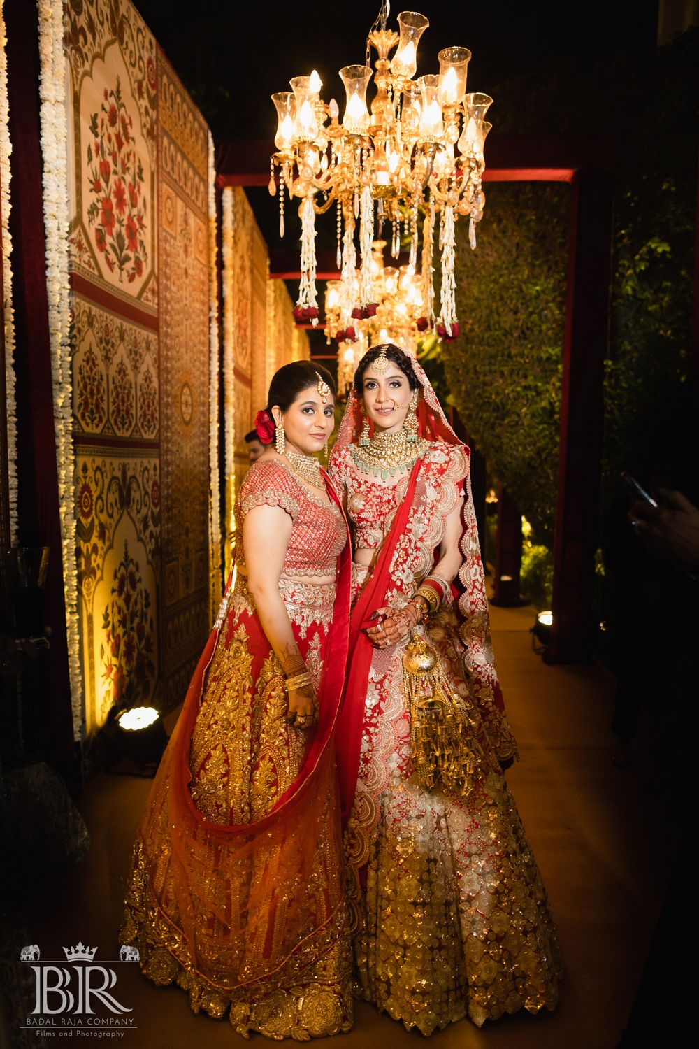 Photo of Bride in a red lehenga posing with a bridesmaid