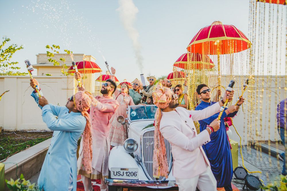Photo of Groom entry in vintage car and party poppers