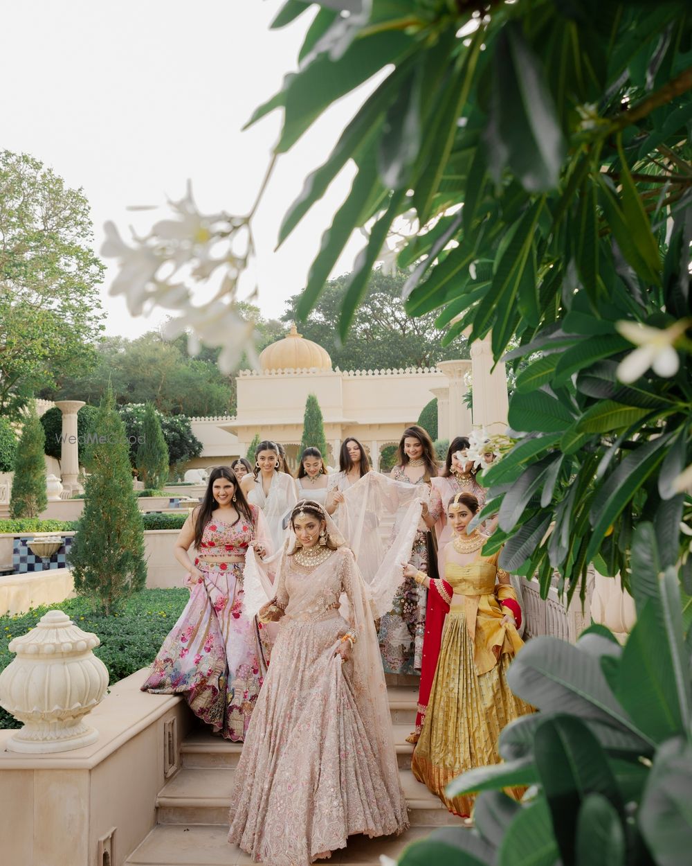 Photo of Stunning candid shot of the bridal entry with the bride entering with her bridesmaids holding her train