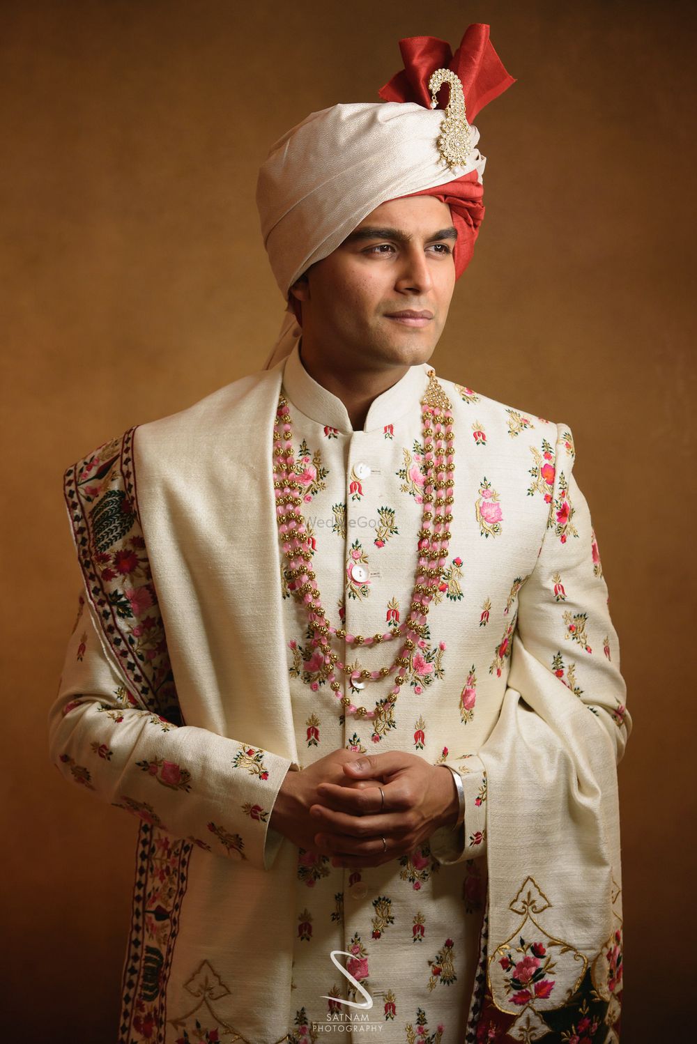 Photo of groom in a white floral sherwani and safa