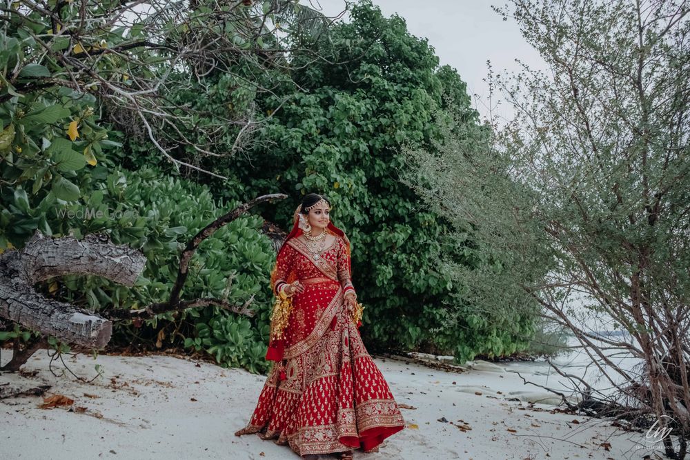 Photo of bride in red posing on her beach wedding