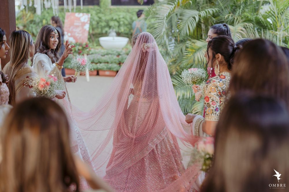 Photo of bride twirling in her peach lehenga with bridesmaids around