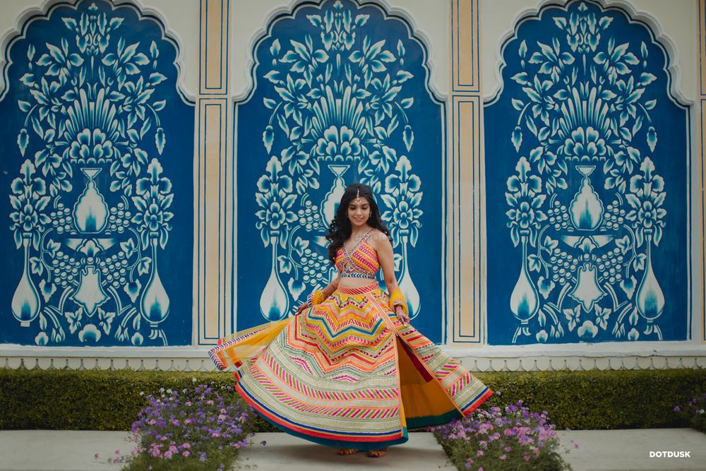 Photo of A twirling bride in a mutlicoloured lehenga with a side slit