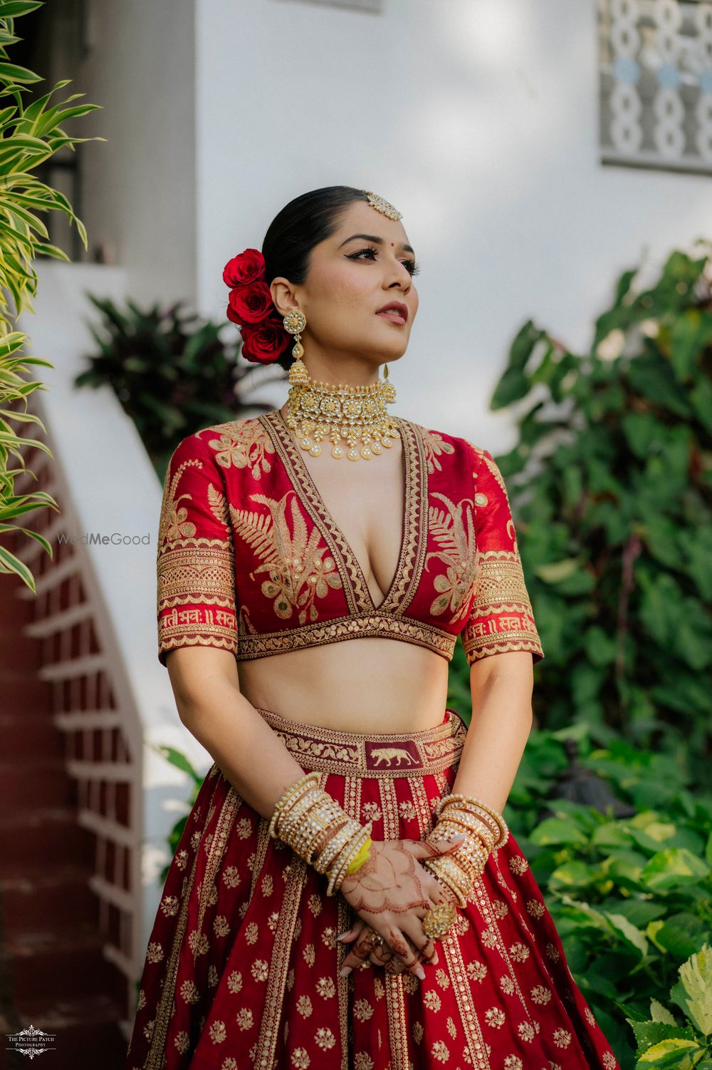 Photo of Gorgeous bridal bun with red roses for wedding day with bride in a Sabyasachi red lehenga