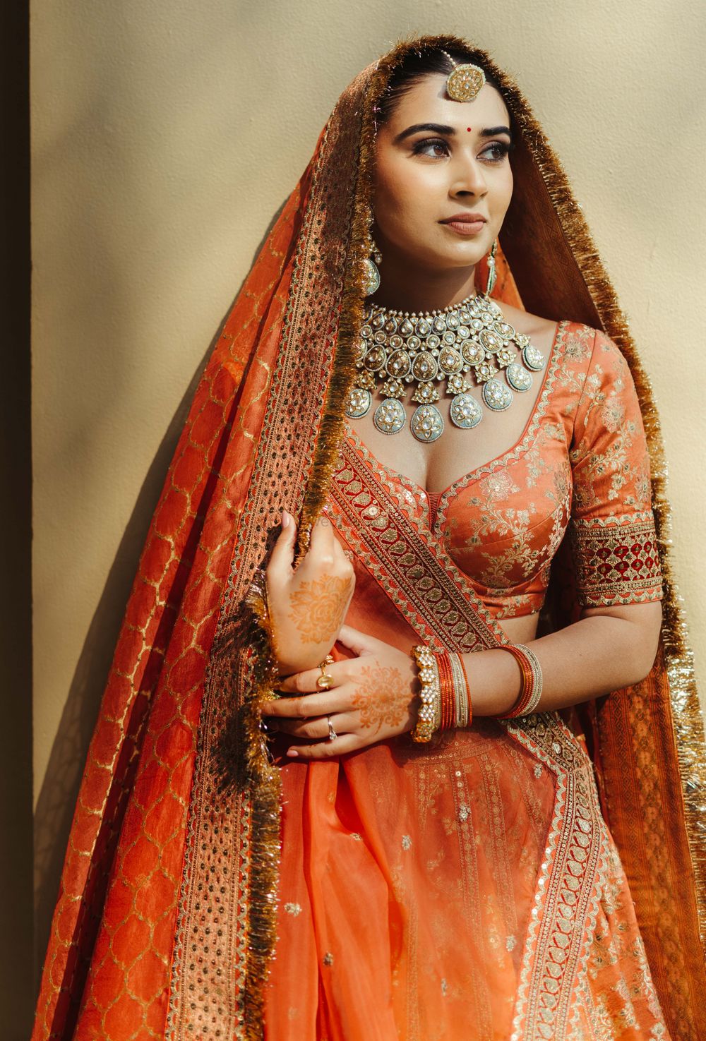 Photo of unique bridal jewellery with an orange lehenga
