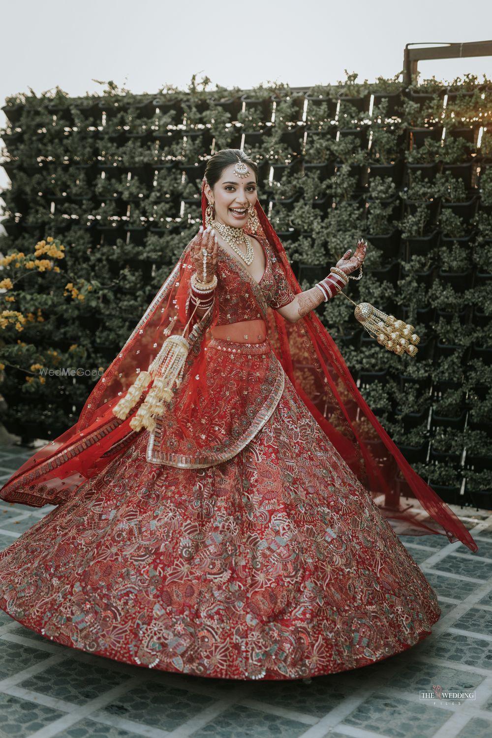 Photo of bride twirling in her orange wedding lehenga with gold kaleeras