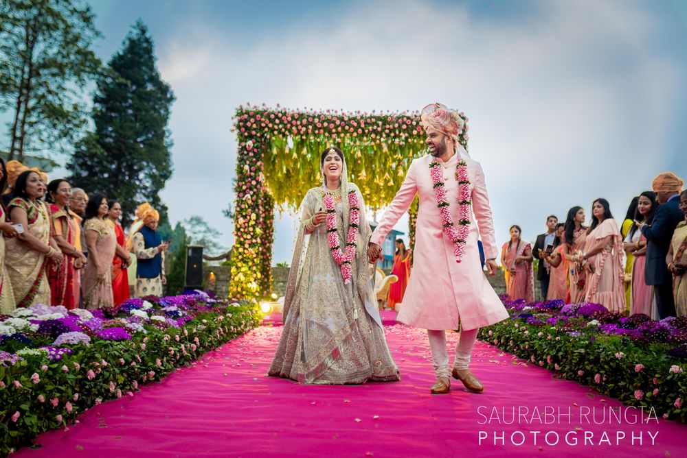 Photo of A couple walks holding hands in front of their mandap