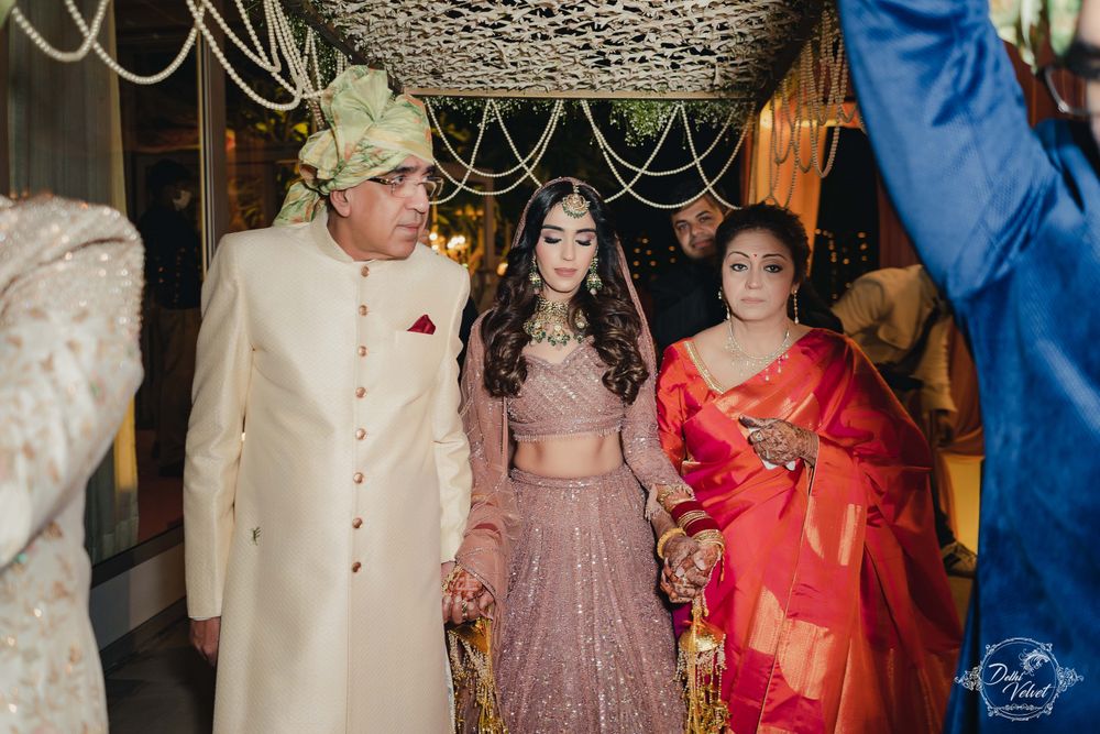 Photo of bride entering her wedding with her parents by her side