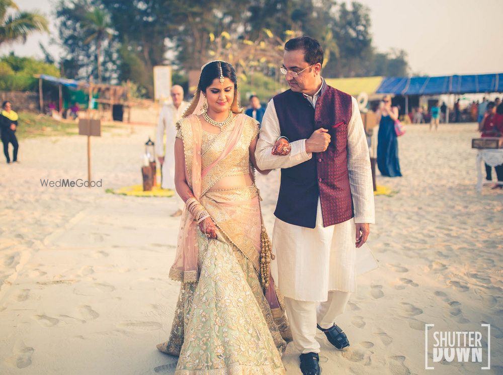 Photo of Bride in pastel lehenga entering beach wedding