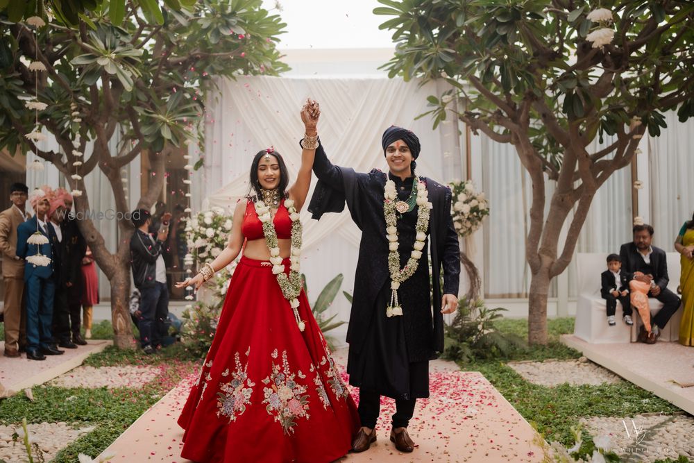 Photo of A just married couple shot with the bride in a bright red lehenga and the groom in a black sherwani