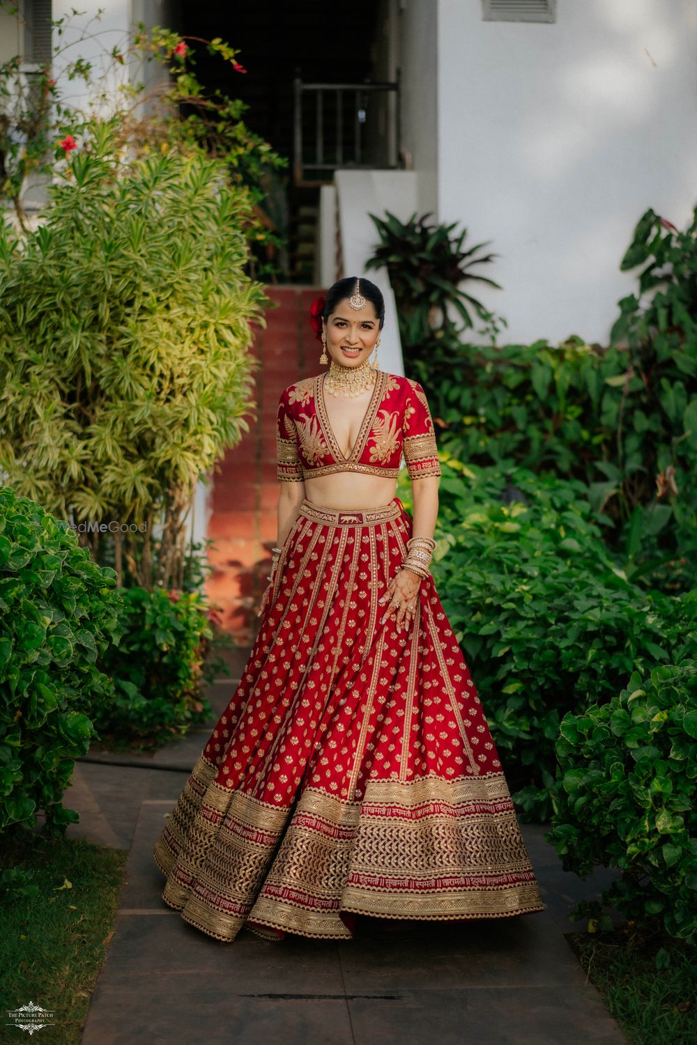 Photo of Stunning bridal portrait with the bride twirling in a Sabyasachi red and gold lehenga and a plunge neck blouse