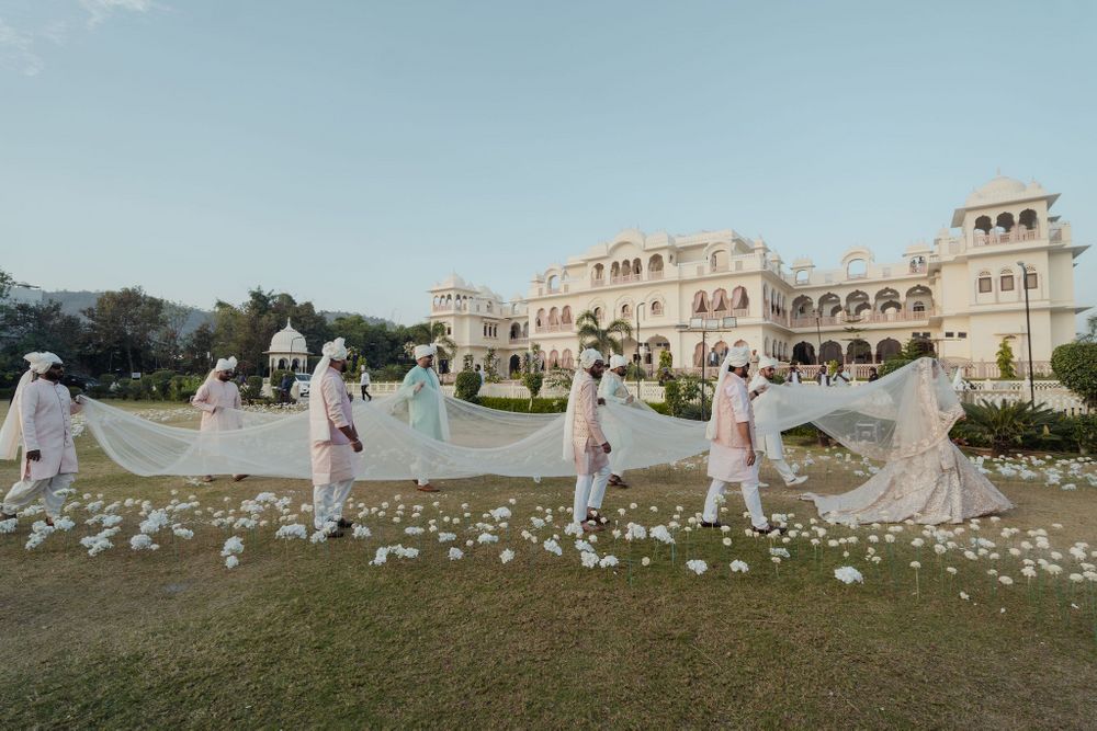 Photo of This grand entry shot with her friends and family carrying a statement veil as she enters on her wedding day