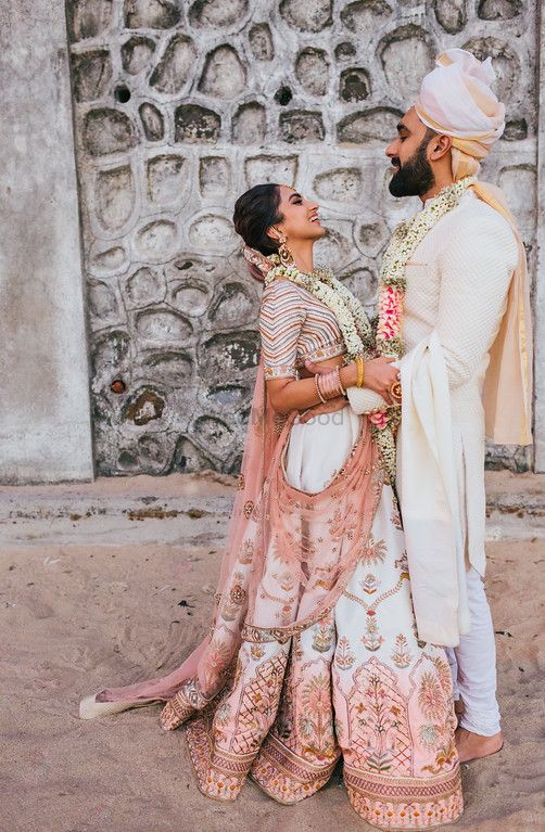 Photo of Bride and groom in ivory with customised lehenga