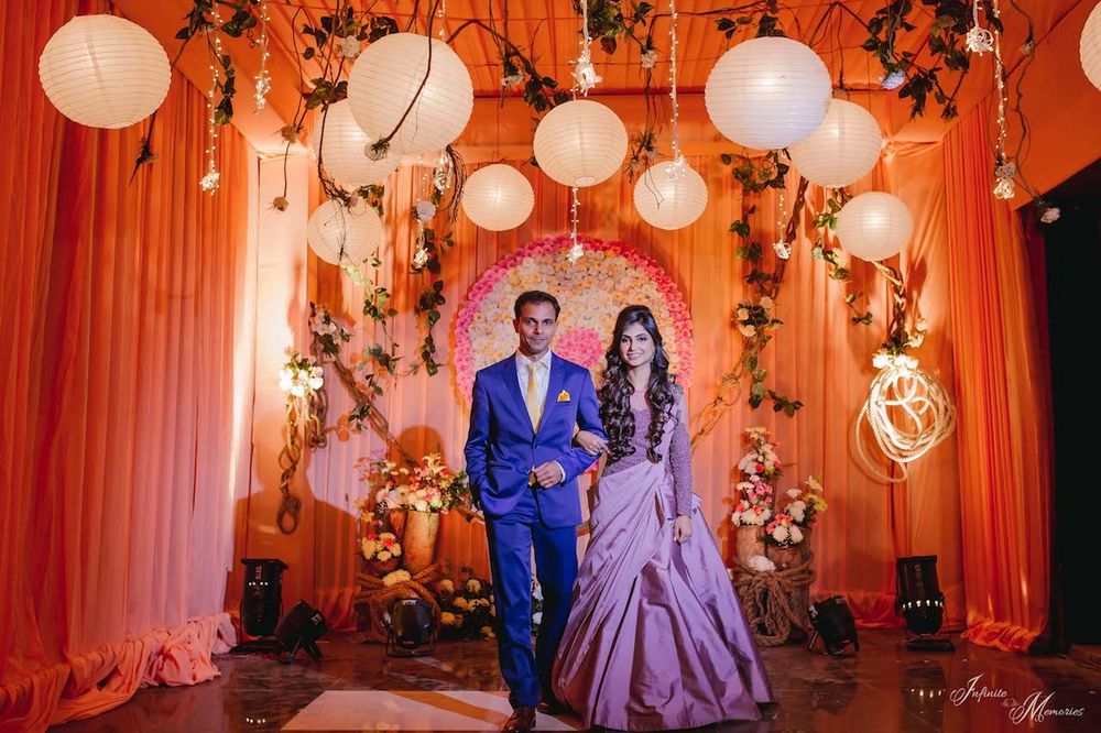Photo of A bride in a gown and a groom in a blue suit enter together for their sangeet/cocktail function.
