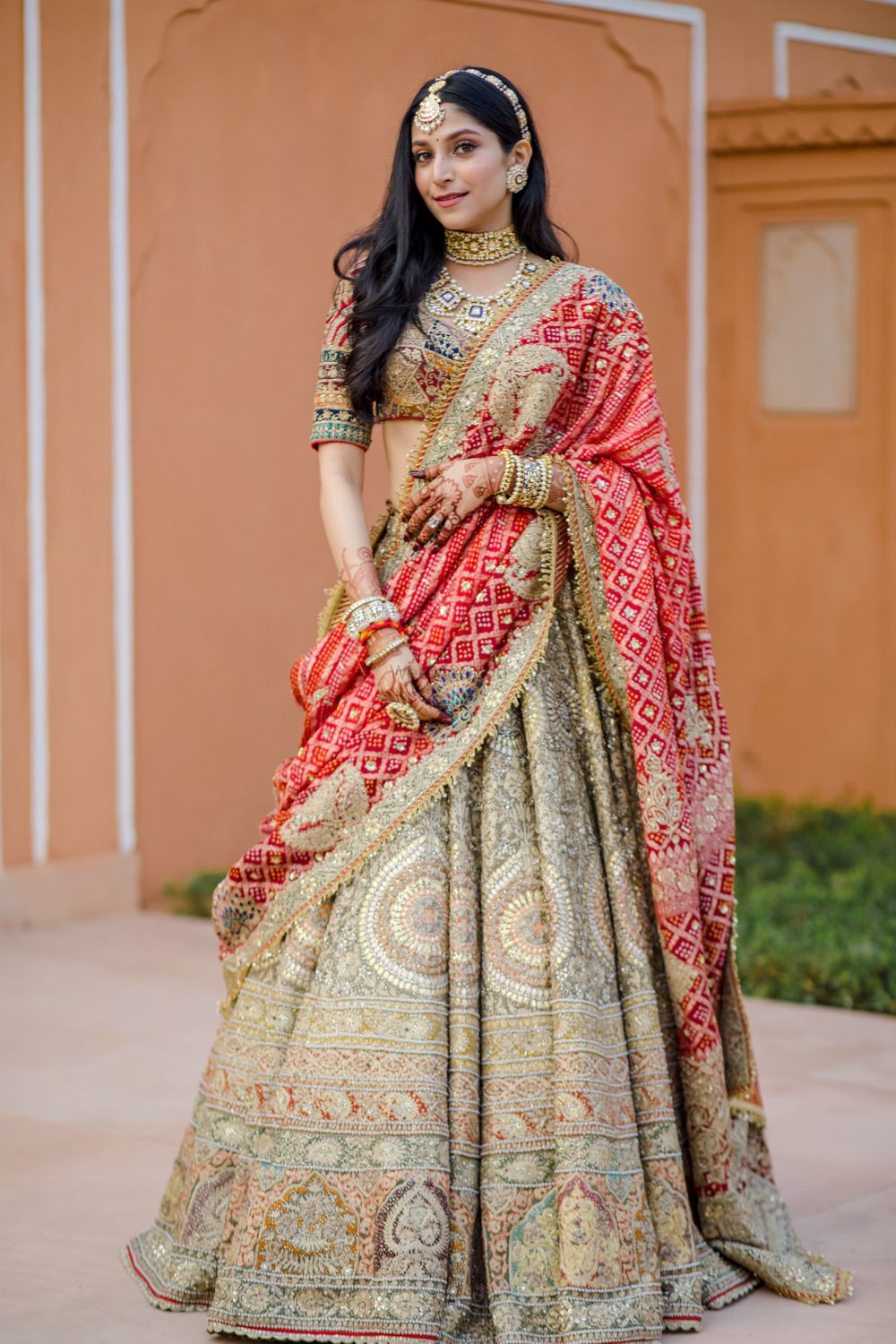 Photo of Bride wearing a heavy lehenga with a red bandhani dupatta.