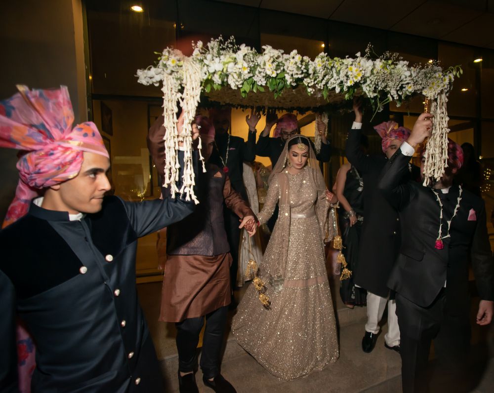Photo of A bridal entry with brothers by her side and a gorgeous phoolon ki chaadar in of white flowers