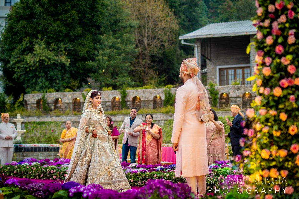 Photo of A bride in a light blue and gold lehenga walking towards her groom