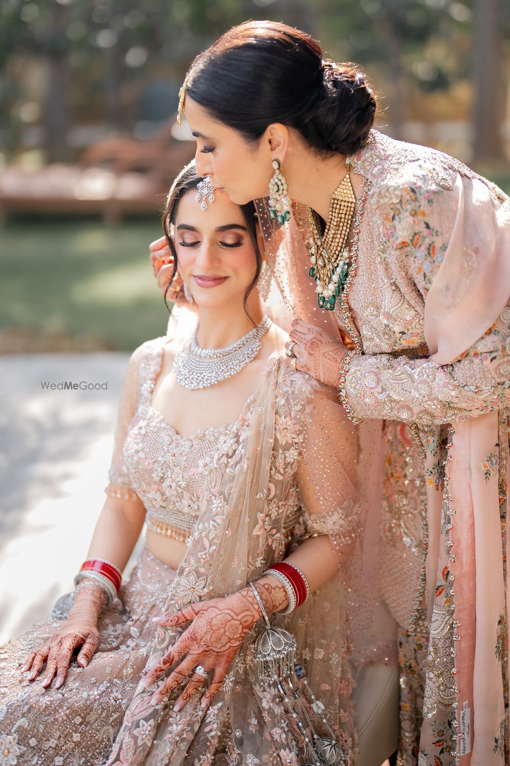 Photo of Lovely shot of the bride and her mother, both in pastel peach outfits, sharing a moment before the wedding