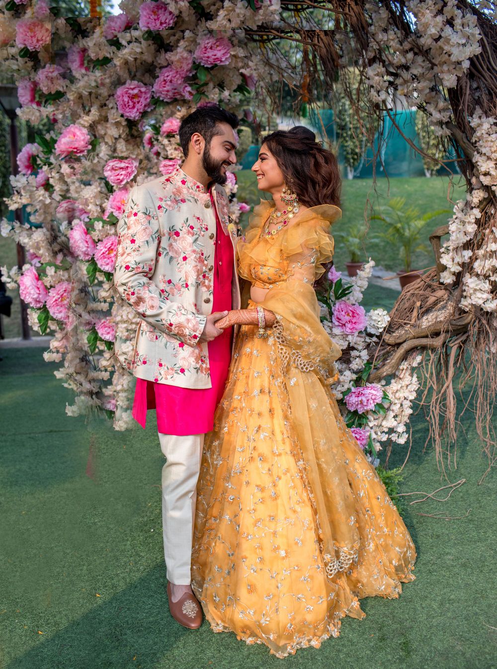 Photo of Mehendi couple portrait with groom in bright outfit and bride in yellow lehenga