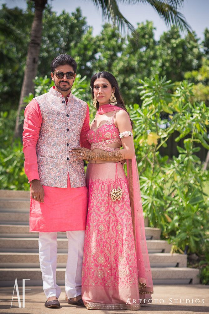 Photo of Matching bride and groom in coral outfits for mehendi