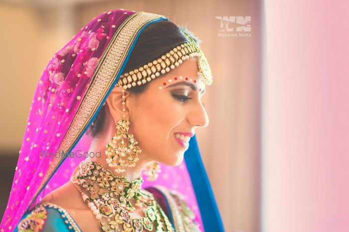 Photo of matha patti and earrings and bridal necklace with green enamel worn with pink dupatta and flowers in hair