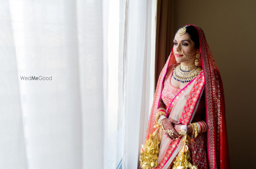 Photo of A bride in a red lehenga with gold kalire posing on her wedding day