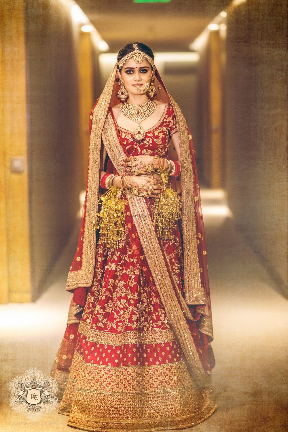 Photo of Red and gold bridal lehenga wearing kaleere