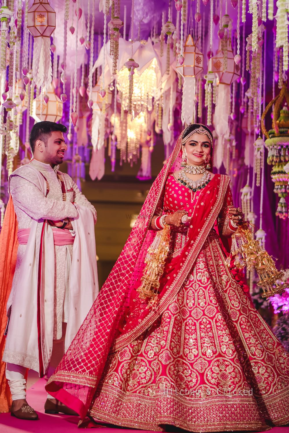 Photo of A shot of the bride in red lehenga twirling as the groom looks on
