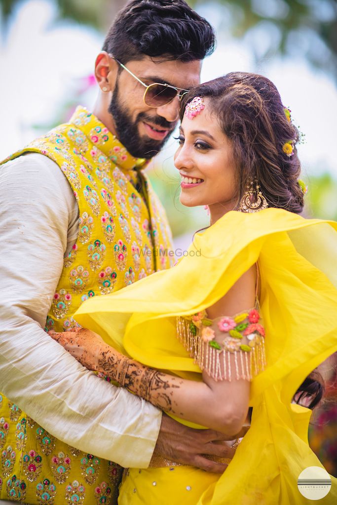 Photo of A bride and groom pose on their mehendi