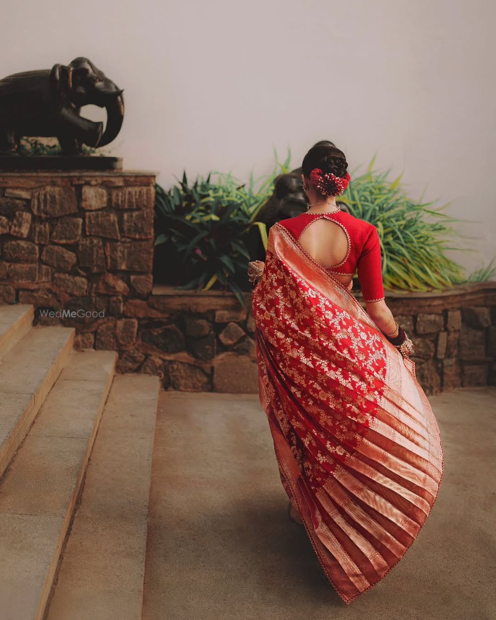 Photo of Red benarasi Sabyasachi saree with cutout blouse and a twisted bridal bun