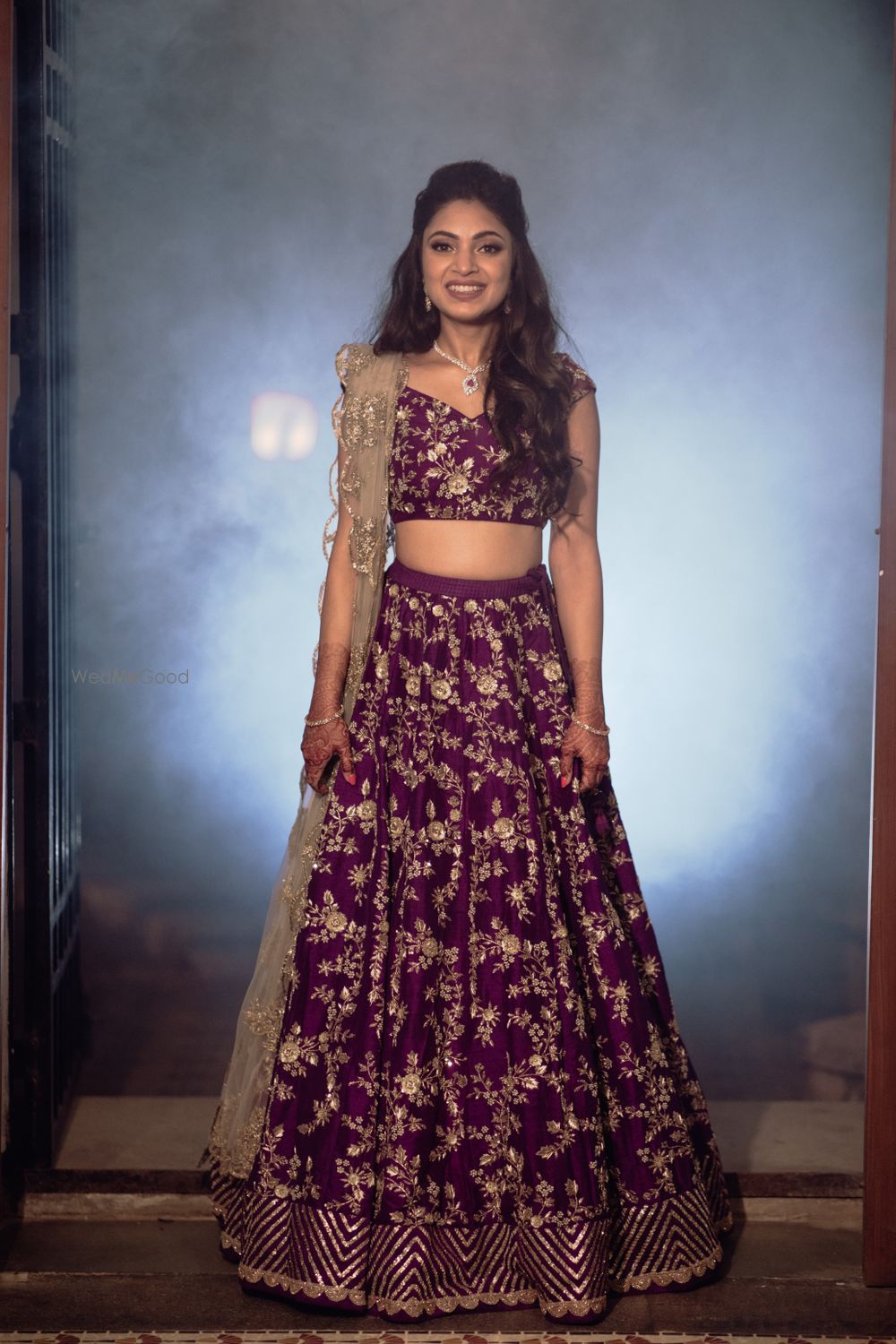 Photo of Bride wearing an aubergine lehenga with a scalloped dupatta.