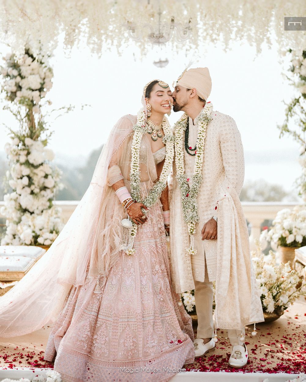 Photo of Pretty shot of the groom kissing the bride as they just got married in a pastel theme wedding