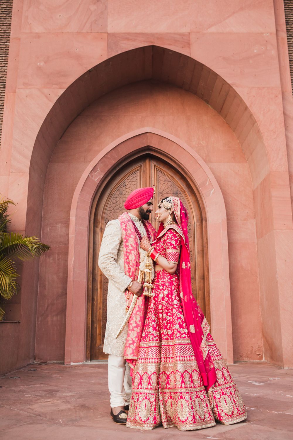 Photo of A sikh bride and groom in coordinated outfits pose on their wedding day