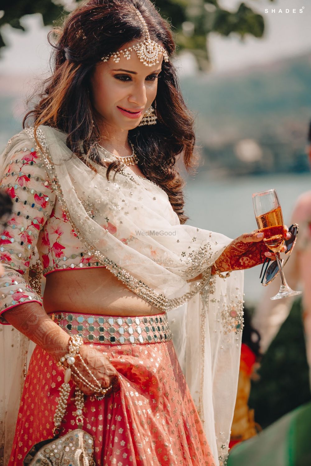 Photo of A bride in a pastel-colored mehndi outfit enjoying champagne