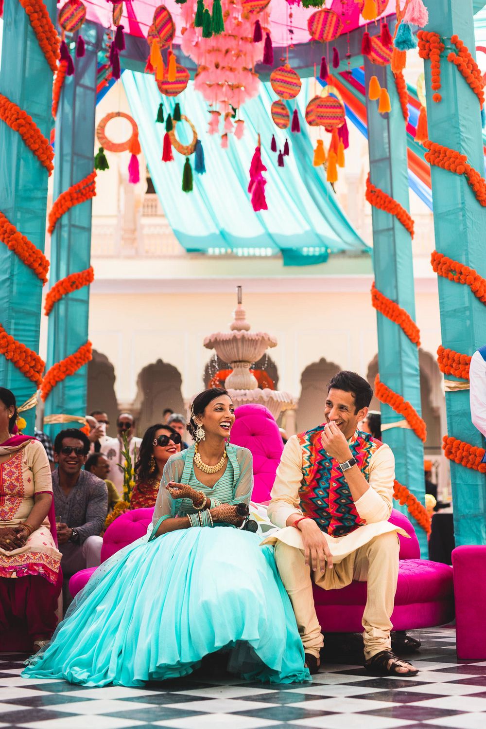 Photo of A couple sits under a colorful tent setup for the mehndi