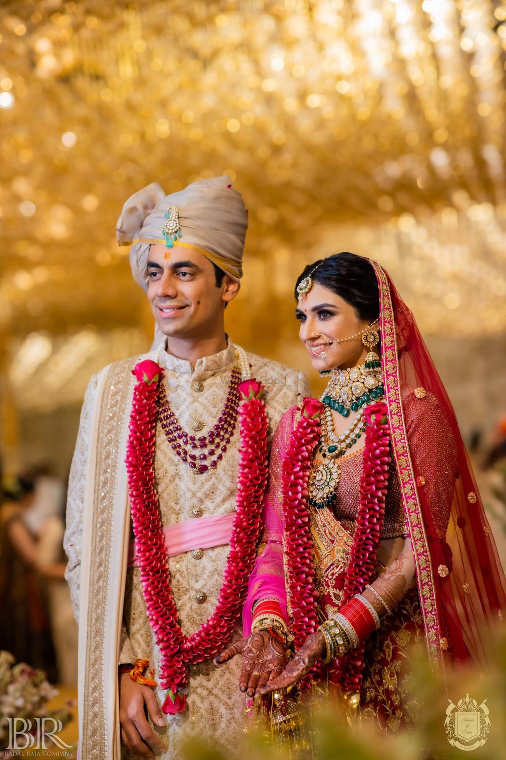 Photo of contrasting bride and groom outfits wearing red jaimalas