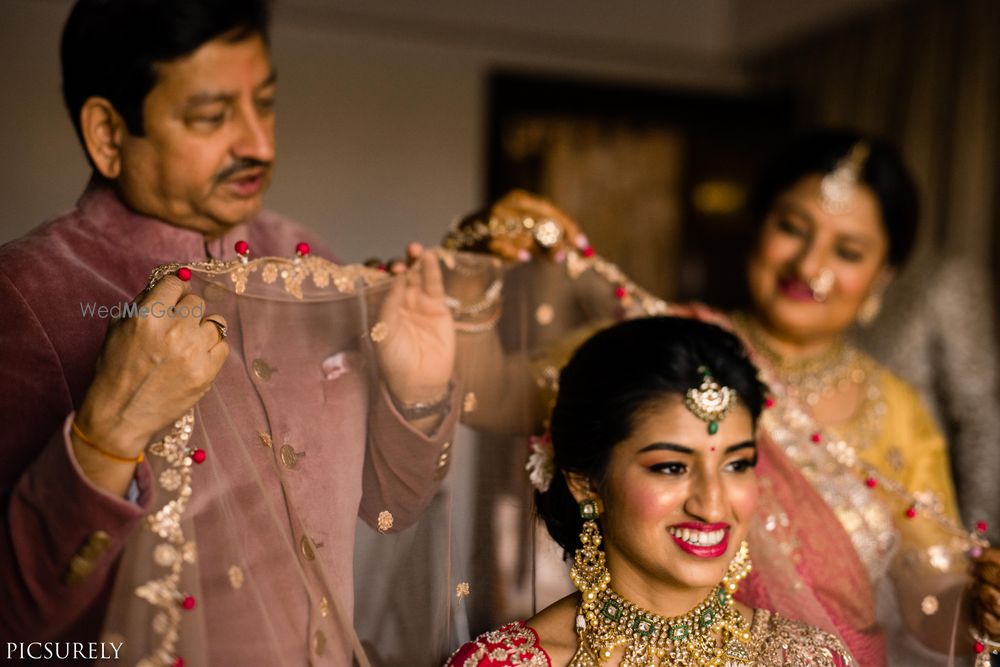 Photo of Bridal portrait with her parents placing dupatta on her head shot