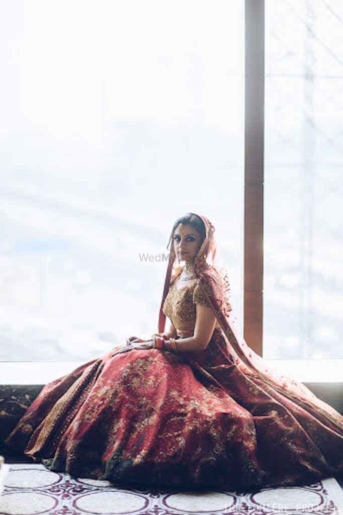 Photo of Bridal portrait with lehenga flared out by the window