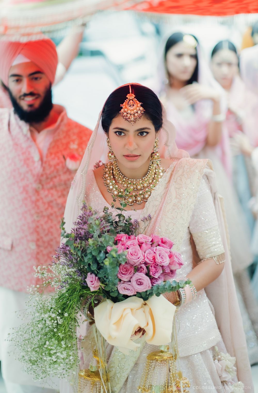 Photo of sikh pastel bride entering her wedding holding a bouquet
