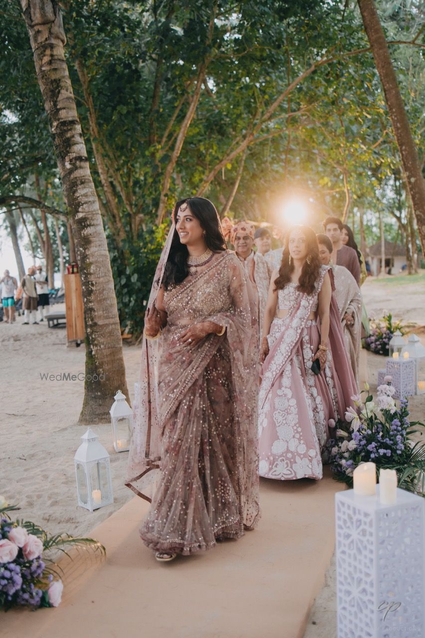 Photo of Bride walking down the aisle in a pastel peach saree for her beach wedding