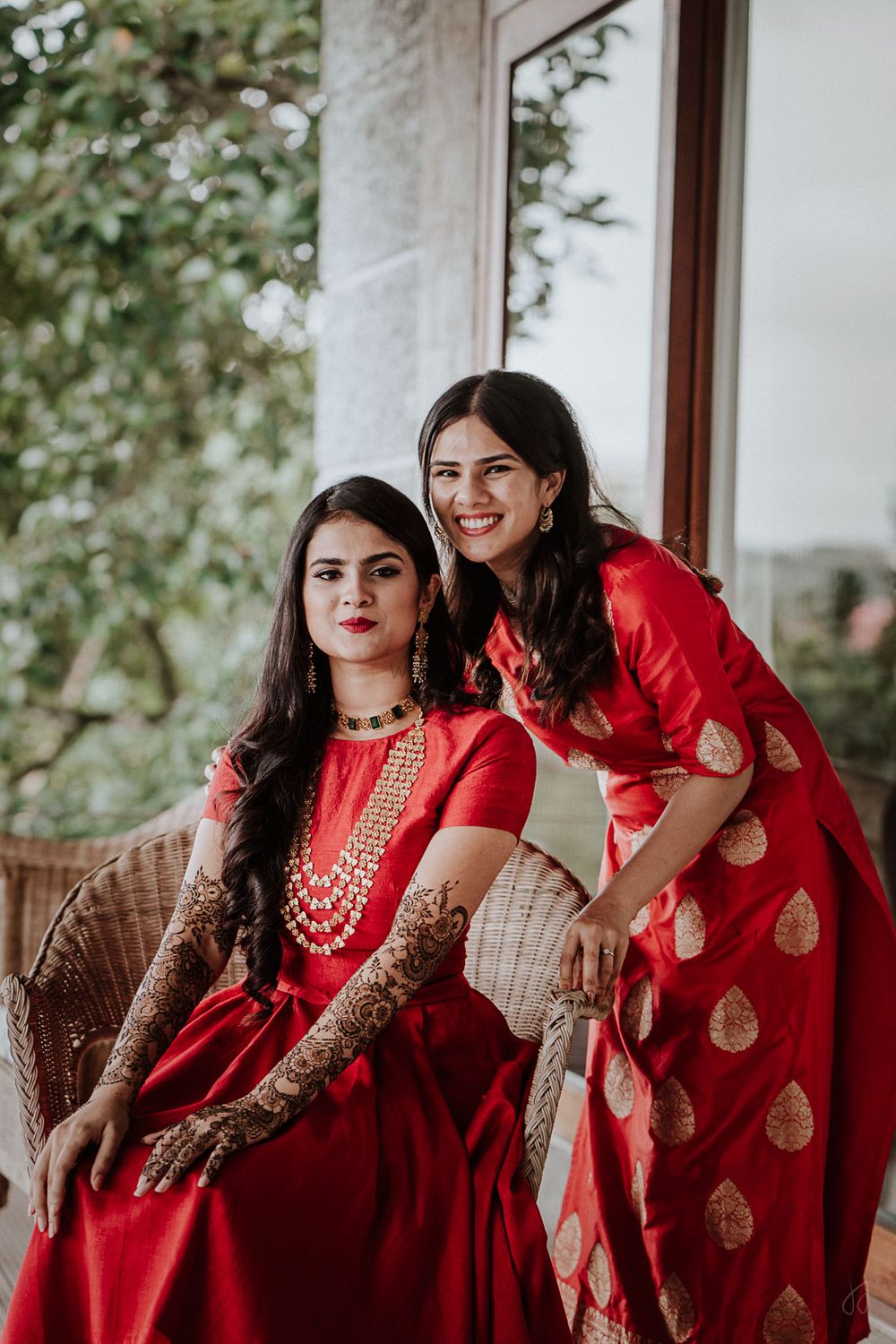 Photo of bridal mehendi look with bride to be matching with her sister in red