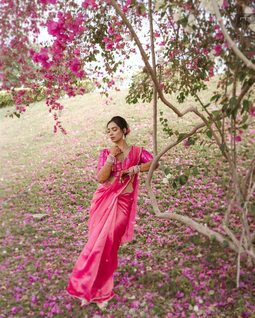 Photo of Lovely bridal portrait against a bougainvillaea tree with the bride in a hot pink saree