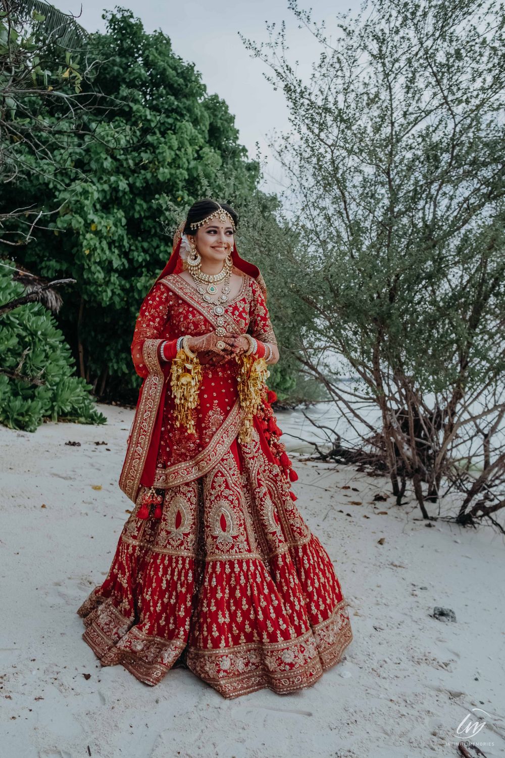 Photo of bride in red posing on beach before the wedding