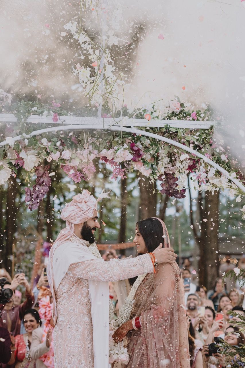 Photo of Candid jaimala ceremony shot of the couple with a flower shower