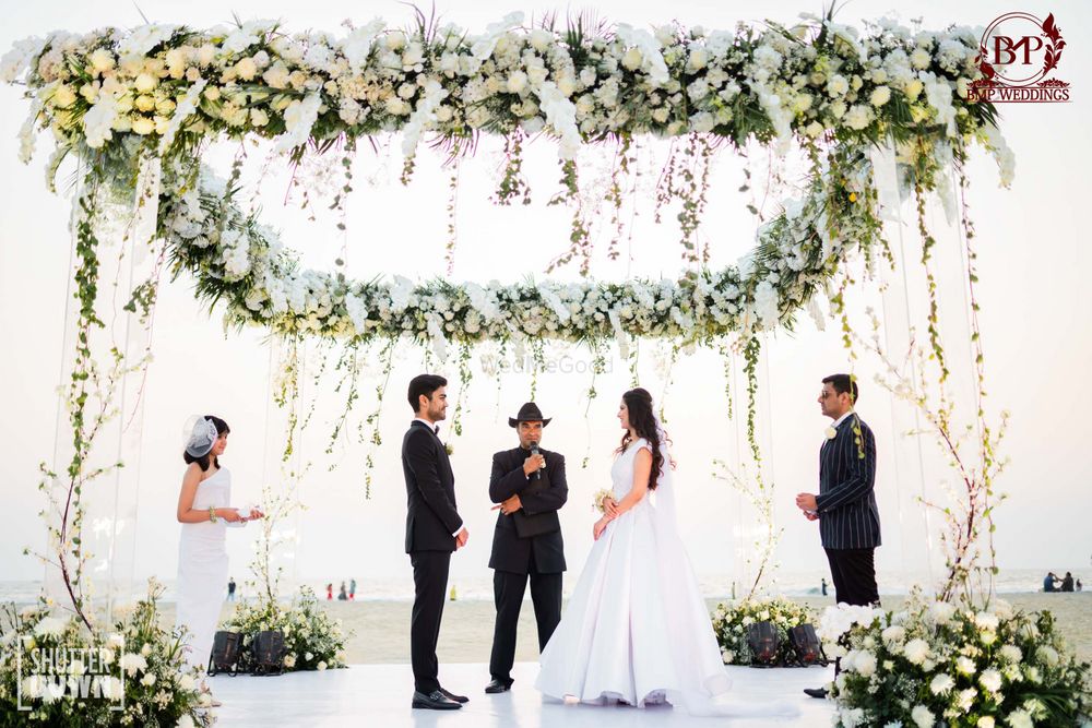 Photo of wedding ceremony under white floral mandap