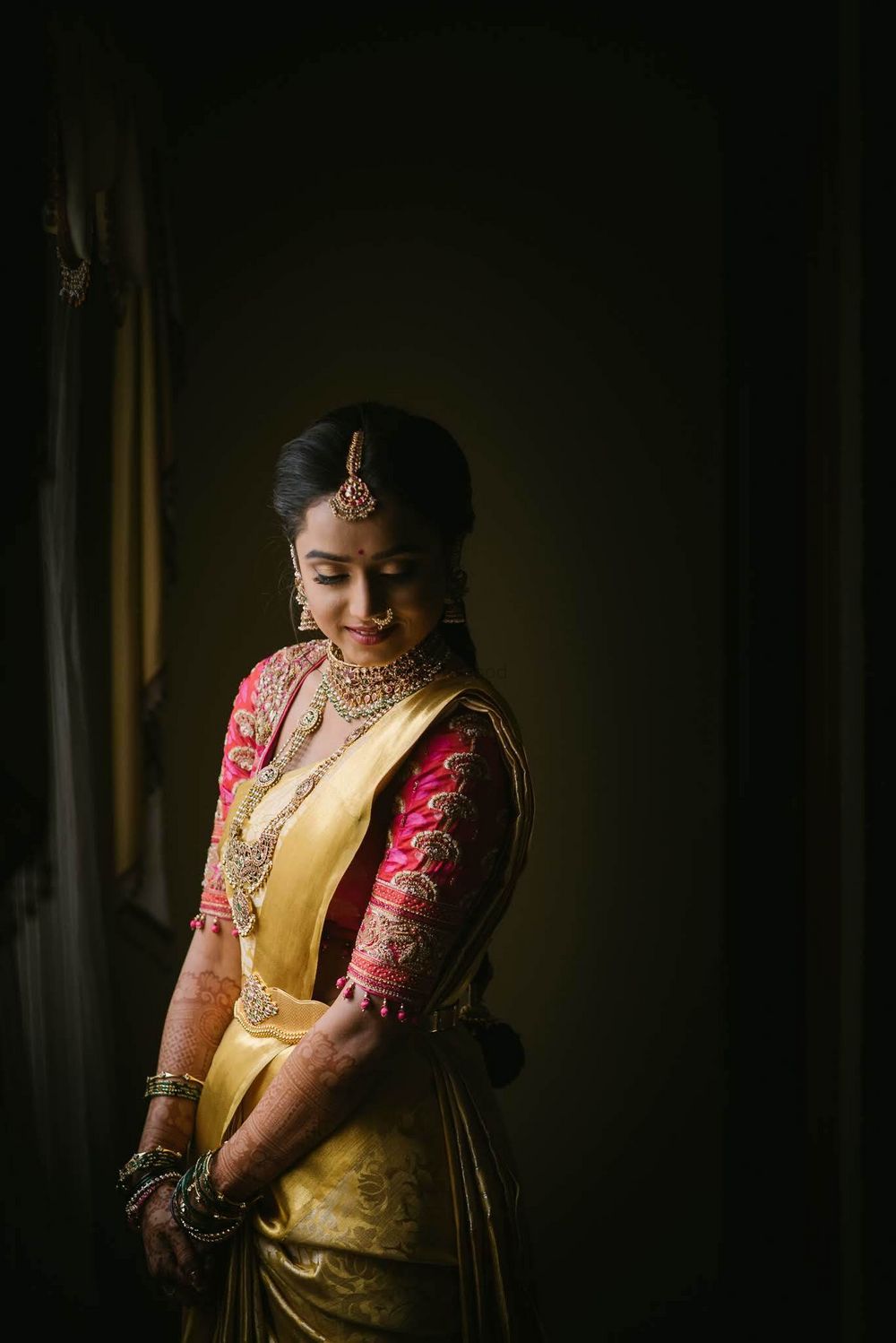 Photo of Bride posing in yellow kanjeevaram saree with an embroidered pink blouse.