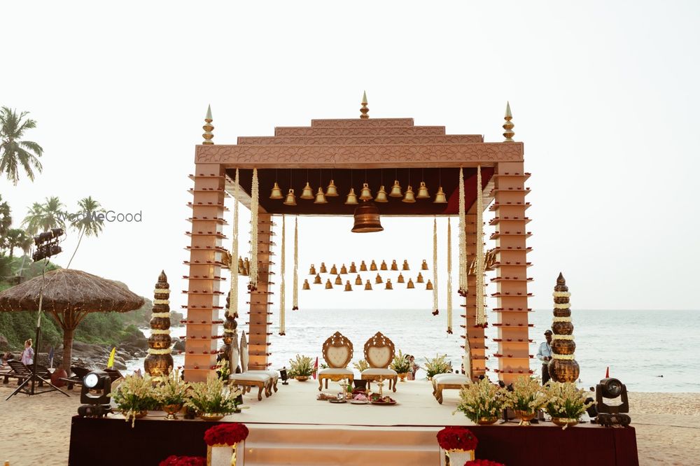 Photo of Gorgeous beach side mandap with hanging brass bells and open air venue
