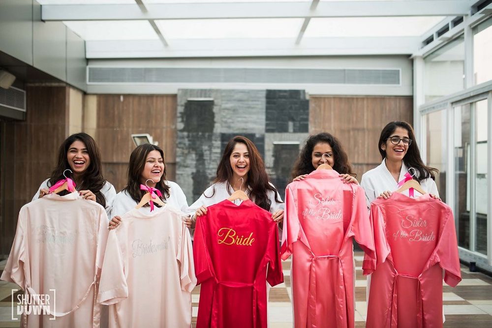 Photo of Bride with bridesmaids holding up personalised robes