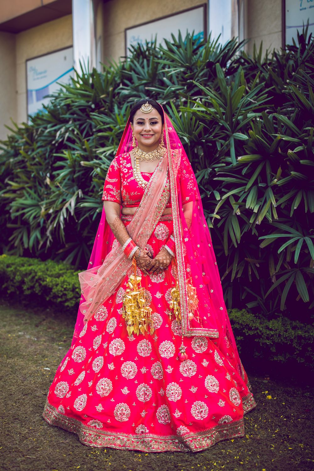 Photo of A beautiful bridal portrait in a bright pink lehenga and gold jewellery.